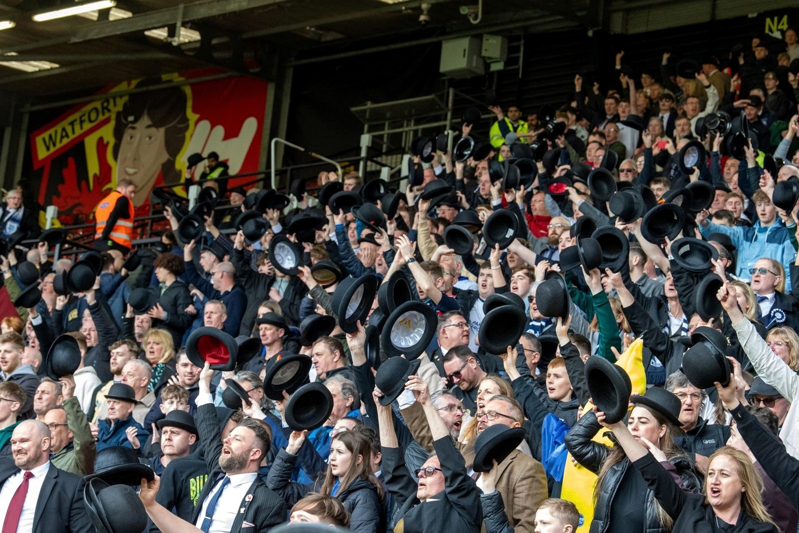 Preston supporters in bowler hats lifting them together in the away end at Charlton.